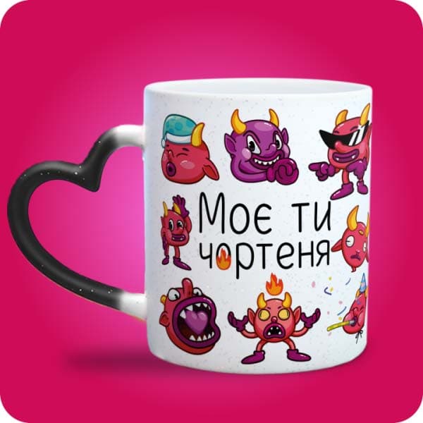 Біла чашка з кумедними кольоровими чортенятами та написом "Моє ти чортеня", вигляд чашки хамелеон з ручкою сердечко
