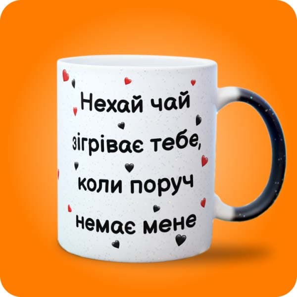 Біла чашка з написом "Нехай чай зігріває тебе, коли поруч немає мене" та маленькими сердечками, вигляд з лівого боку