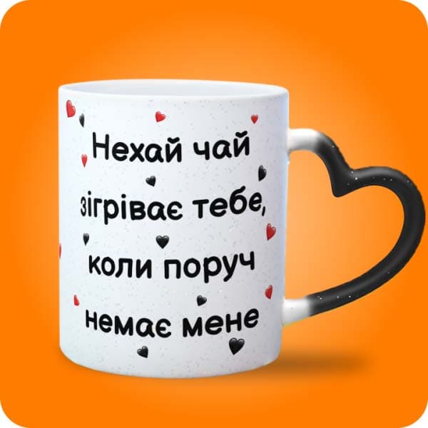 Біла чашка з написом "Нехай чай зігріває тебе, коли поруч немає мене" та маленькими сердечками, вигляд чашки хамелеон з ручкою сердечко