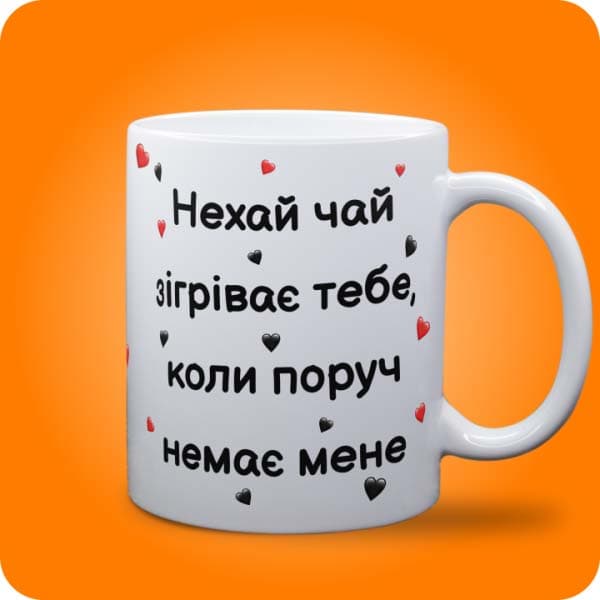 Біла чашка з написом "Нехай чай зігріває тебе, коли поруч немає мене" та маленькими сердечками, вигляд чашки біла з блискітками і без блискіток