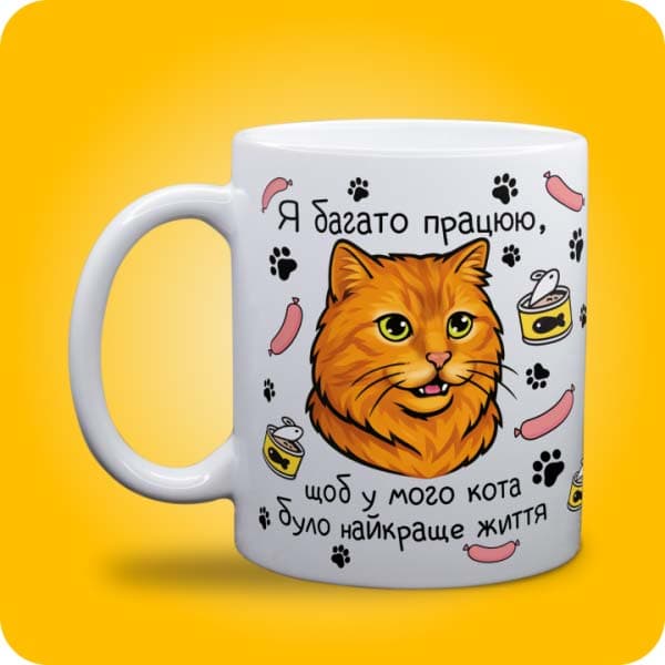 Біла чашка з рудим котом і написом "Я багато працюю, щоб у мого кота було найкраще життя", вигляд чашки біла з блискітками і без блискіток
