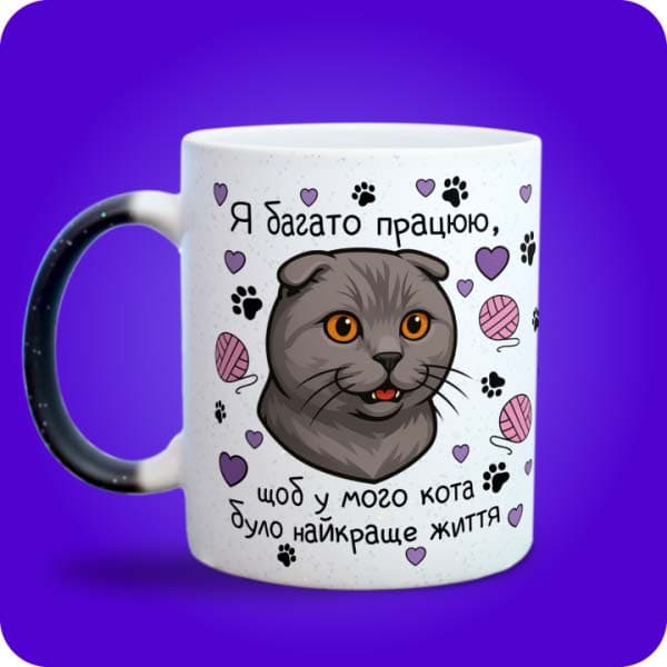 Біла чашка з шотландською висловухою кішкою, сердечками, клубками та написом про найкраще котяче життя, вигляд з лівого боку