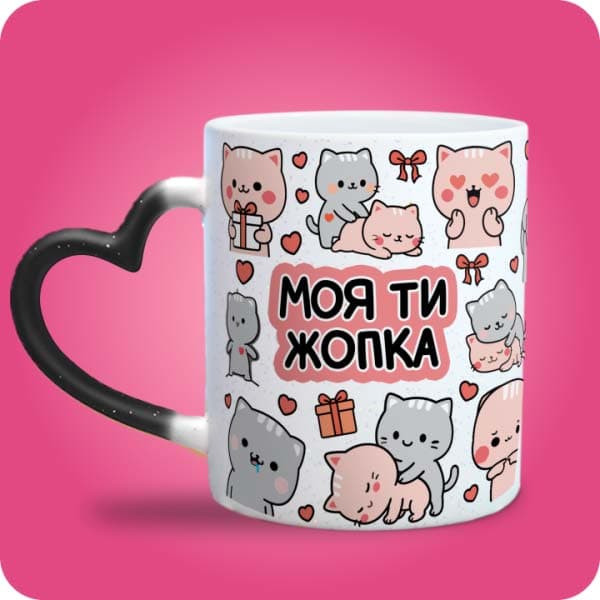 Біла чашка з різнокольоровими котиками, сердечками, подарунками та написом "Моя ти жопка", вигляд чашки хамелеон з ручкою сердечко