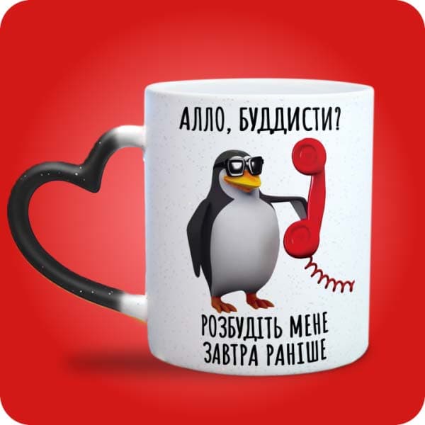 Біла чашка з пінгвіном, телефоном і написом "Алло, буддисти? Розбудіть мене завтра раніше", вигляд чашки хамелеон з ручкою сердечко