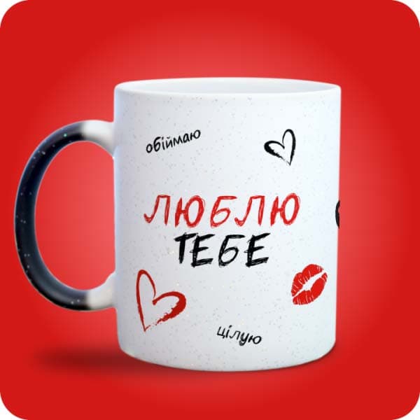 Біла чашка з написом "Люблю тебе", сердечками та червоним поцілунком, вигляд з лівого боку