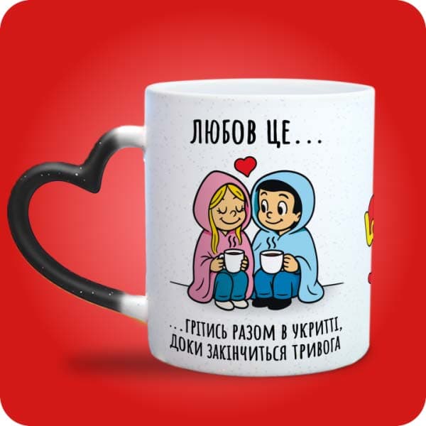 Біла чашка в стилі Love is із закоханою парою під ковдрою та написом "Грітись разом в укритті, доки закінчиться тривога", вигляд чашки хамелеон з ручкою сердечко